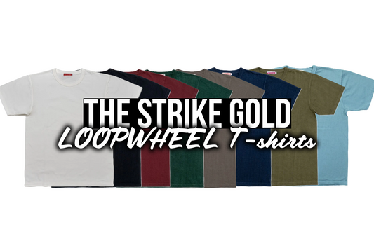 The Strike Gold loopwheel T-shirt lined up in eight indigo, olive, and neutral colorways on a white ground